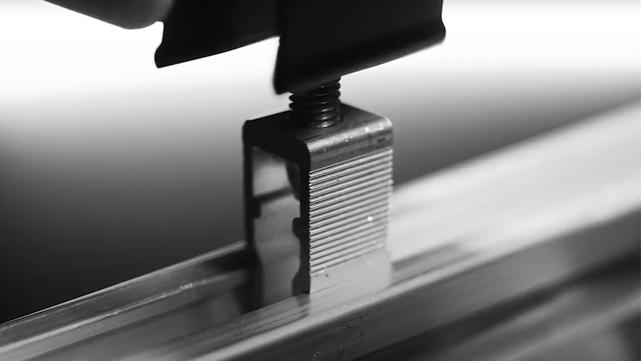 A close-up of a screw being tightened with a tool on a metal object, captured in black and white.