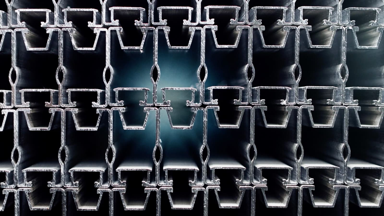 Close-up view of stacked metal profiles with a symmetrical pattern, creating a geometric tunnel effect in the center.
