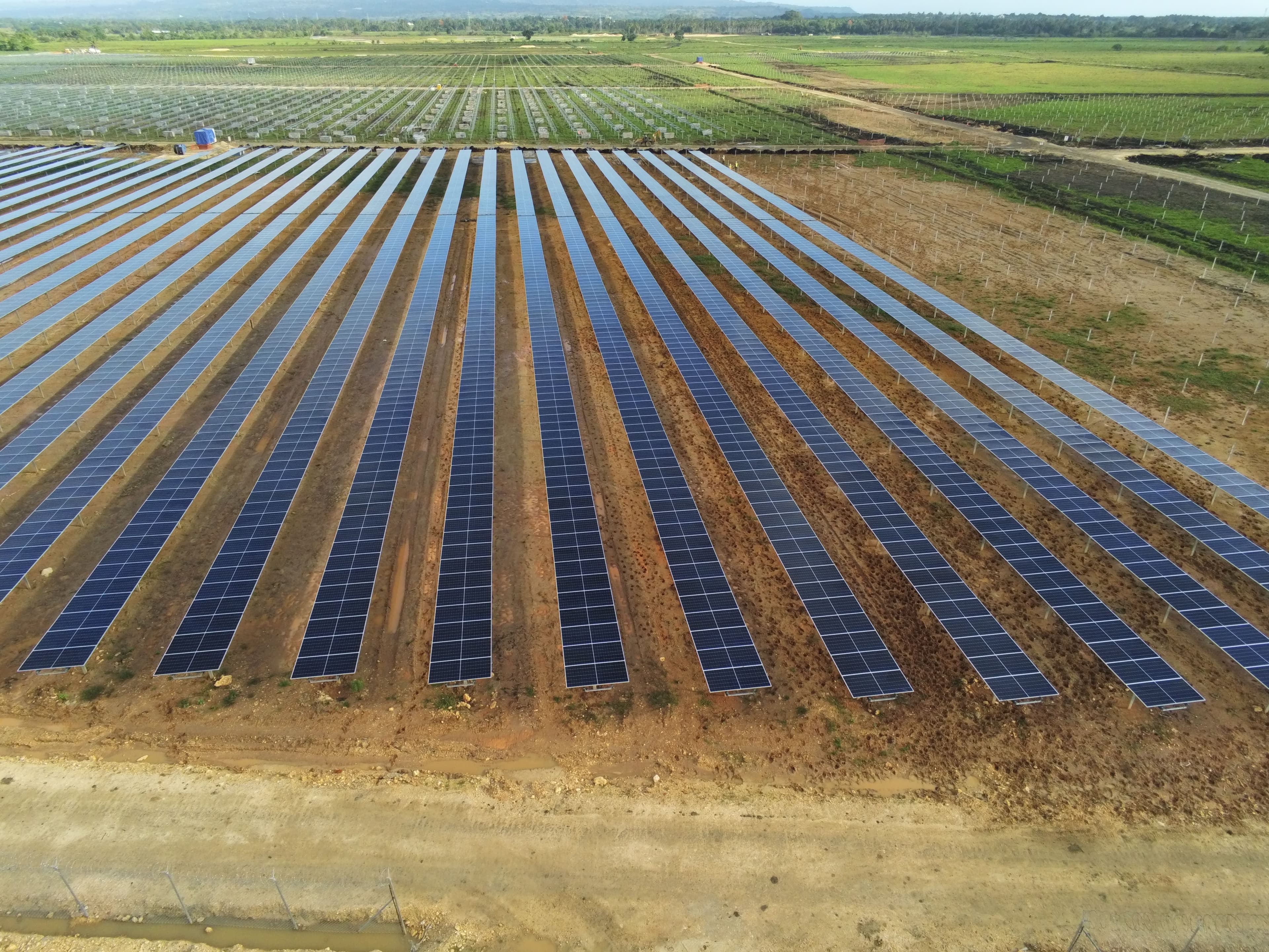 Aerial view of a large solar farm with rows of solar panels spanning a vast field.